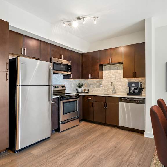 A kitchen with a refrigerator, microwave, oven, and sink.
