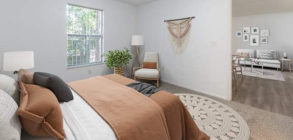 A bedroom with a bed, a chair, a couch, and a wall hanging.