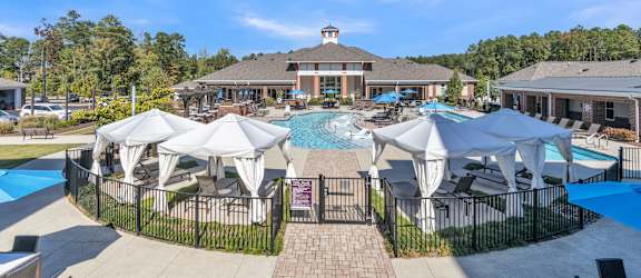 A large swimming pool surrounded by white umbrellas and lounge chairs.at The Aster Cary, Cary