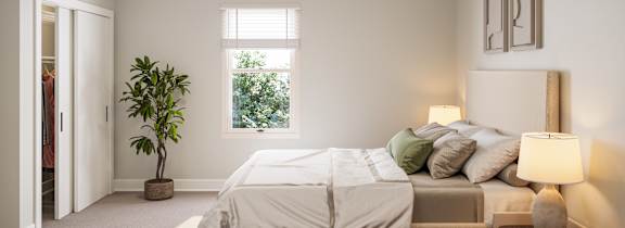 A bedroom with a bed, a plant, and a lamp.