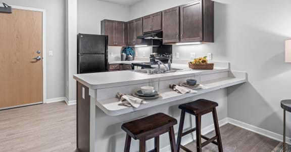 a kitchen with a breakfast bar and stools next to a kitchen counter with a