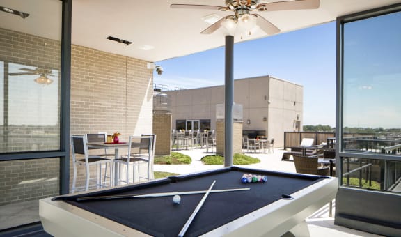 a pool table in a patio area with a ceiling fan