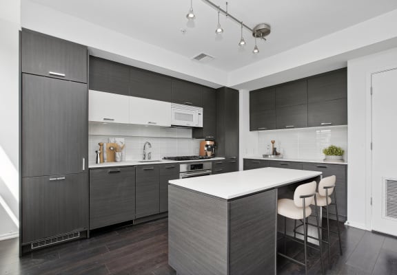 a kitchen with white countertops and dark cabinets