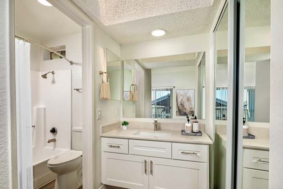 A white bathroom with a toilet, sink, and mirror.