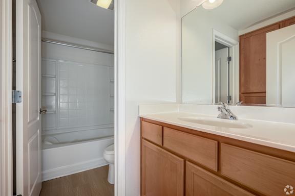 A bathroom with a wooden vanity and a white bathtub.