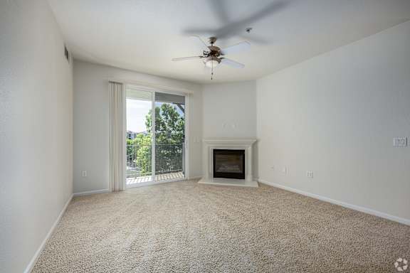 A room with a carpet floor, a ceiling fan, and a fireplace.