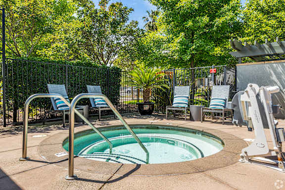A small pool surrounded by chairs and trees.
