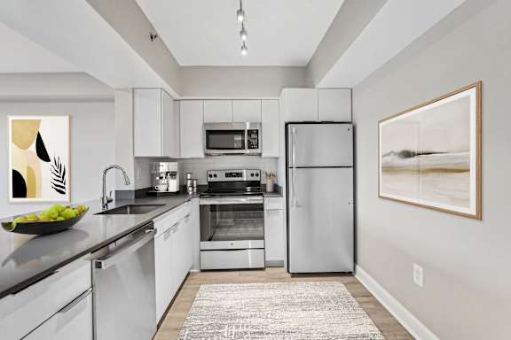 a modern kitchen with stainless steel appliances and white cabinets