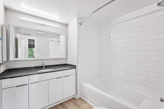 a white bathroom with a tub and a sink and a mirror