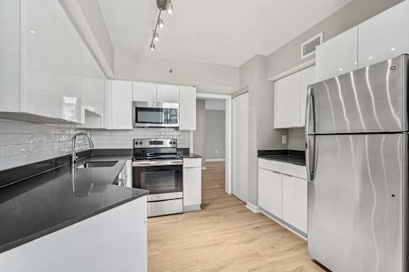 a modern kitchen with stainless steel appliances and white cabinets