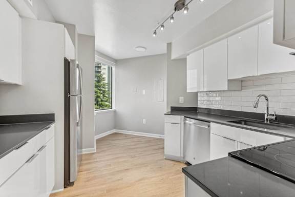 an empty kitchen with white cabinets and black counter tops