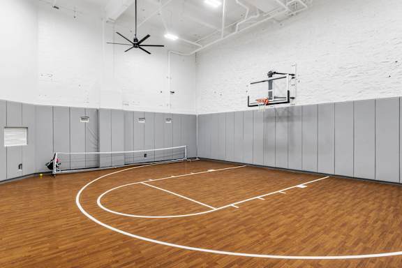 A basketball court with a wooden floor and a basketball hoop.