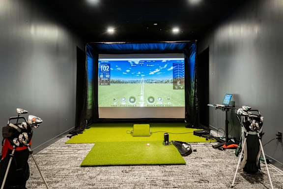 A golf simulator room with a screen showing a golf game.