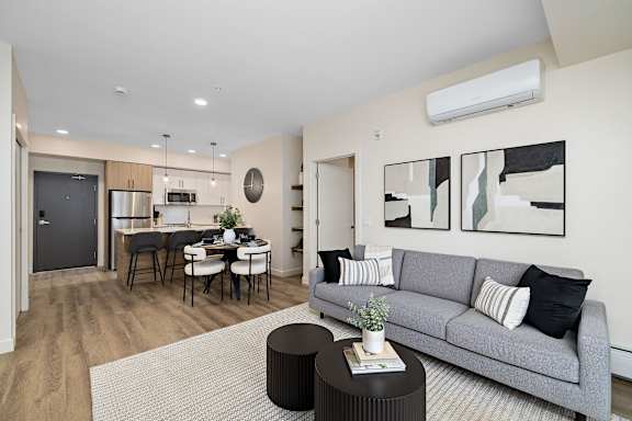 A modern living room with a grey sofa and a dining table.
