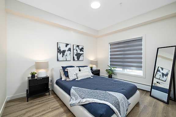 A bedroom with a bed, nightstands, and a window with blinds.at The Fifth at Palisades, Edmonton, AB, T6V 0N5