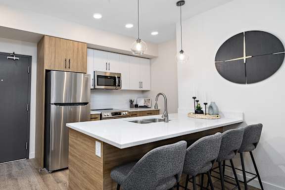 A modern kitchen with a large island and grey chairs.