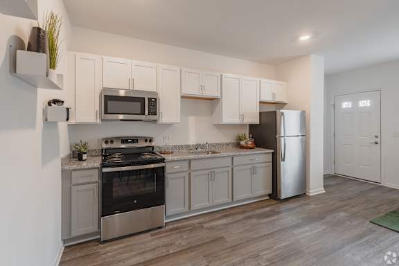 A kitchen with a stove, oven, refrigerator, and microwave.