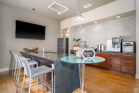 A modern kitchen with a glass table and stainless steel chairs.