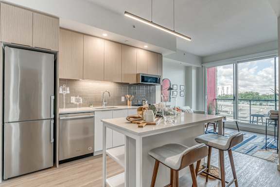A modern kitchen with a refrigerator, stove, and bar stools.