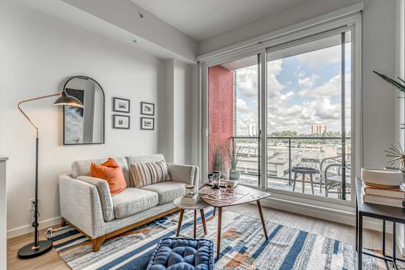 A living room with a grey couch, a table with a bowl on it, and a floor lamp.