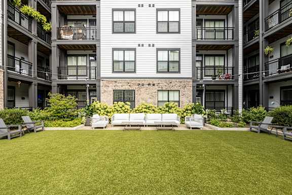 A large grassy area in front of a building with balconies.