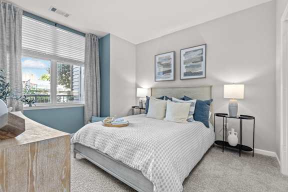 A bedroom with a large bed and a window with curtains.