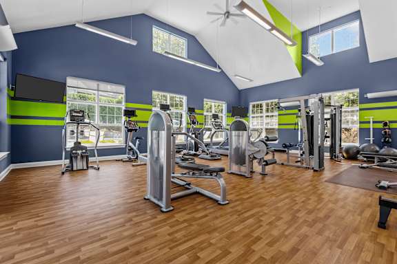A gym with a variety of equipment and a wooden floor.