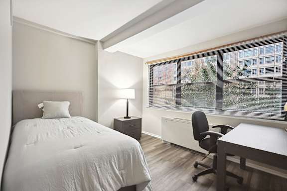 a bedroom with a bed and a desk and a large window