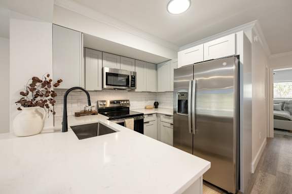 A modern kitchen with a stainless steel refrigerator and white countertops.