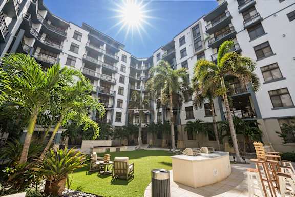 A sunny day at a courtyard with palm trees and a hot tub.