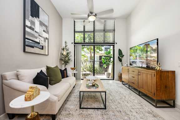 A living room with a white couch, a coffee table, and a flat screen TV.