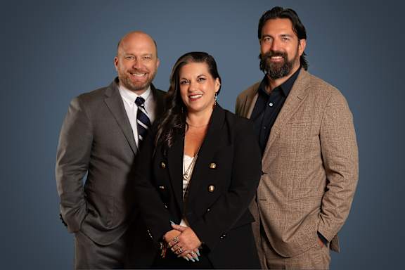 Three people in business attire stand side by side.