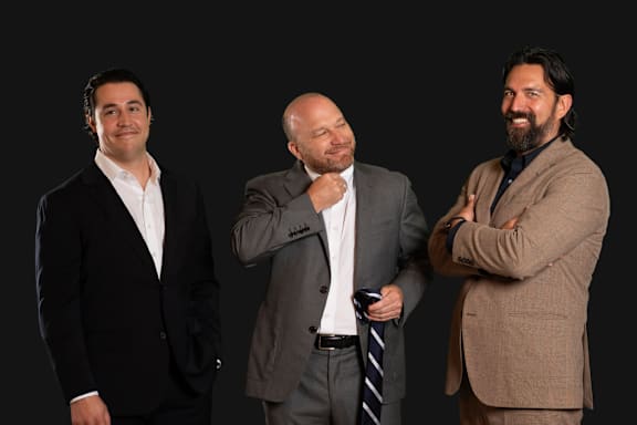 Three men in suits are standing together.