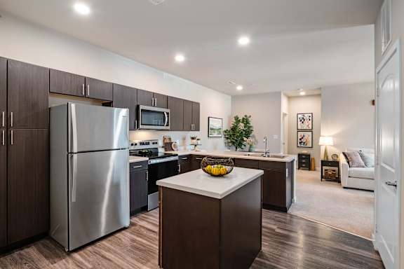 A modern kitchen with a refrigerator, microwave, and oven.