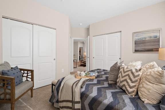 A bedroom with a bed, a chair, and a painting on the wall.