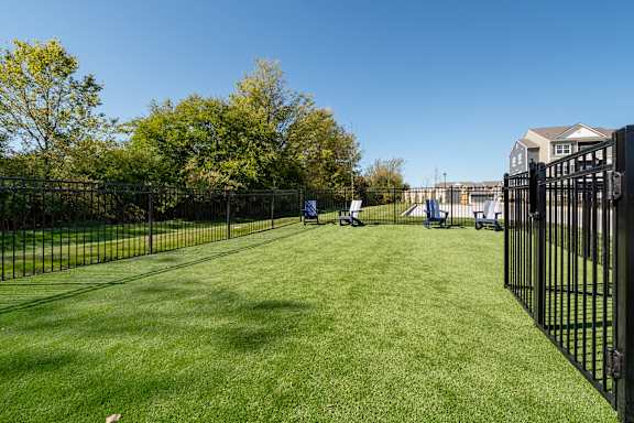 A black fence surrounds a green lawn with trees in the background.