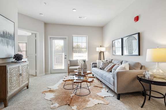A living room with a grey couch, a black table, and a cowhide rug.