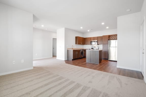 an empty living room with a kitchen with stainless steel appliances  at Aventura at Hawk Ridge, Lake St Louis, Missouri