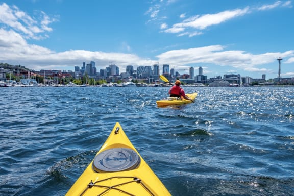 a man in a yellow kayak on the water with a city in the background at Liza Apartments, Seattle, Washington, 98102
