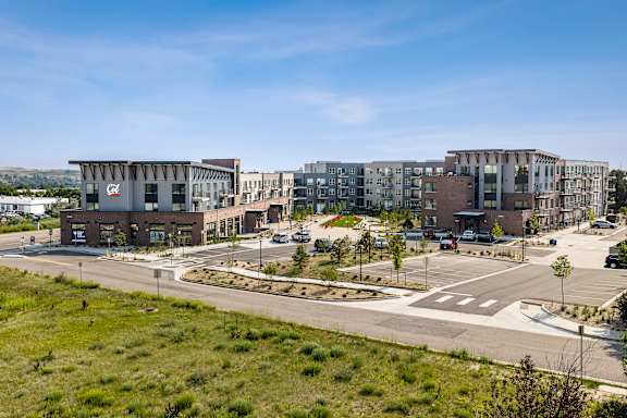 A modern building complex with a grassy area in front.