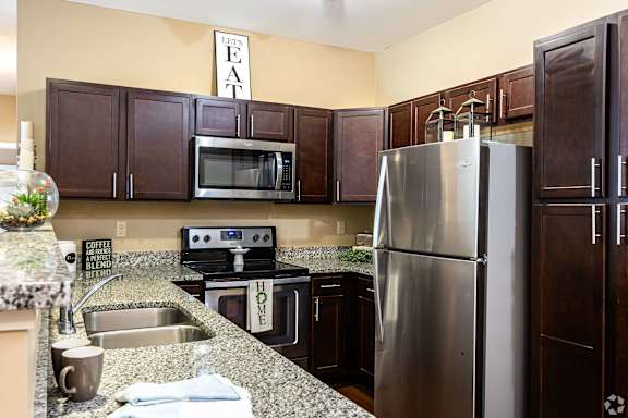 A kitchen with a refrigerator, sink, and cabinets.