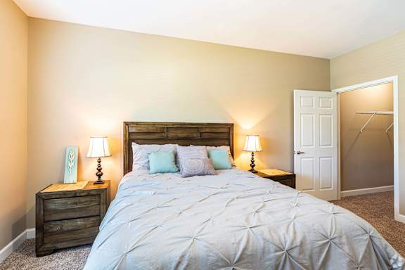 A bedroom with a large bed and two lamps on either side of the bed.