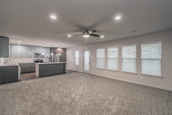 Modern open-concept living room with ceiling fan and wood-style floors at Reserve on Abrams Dallas