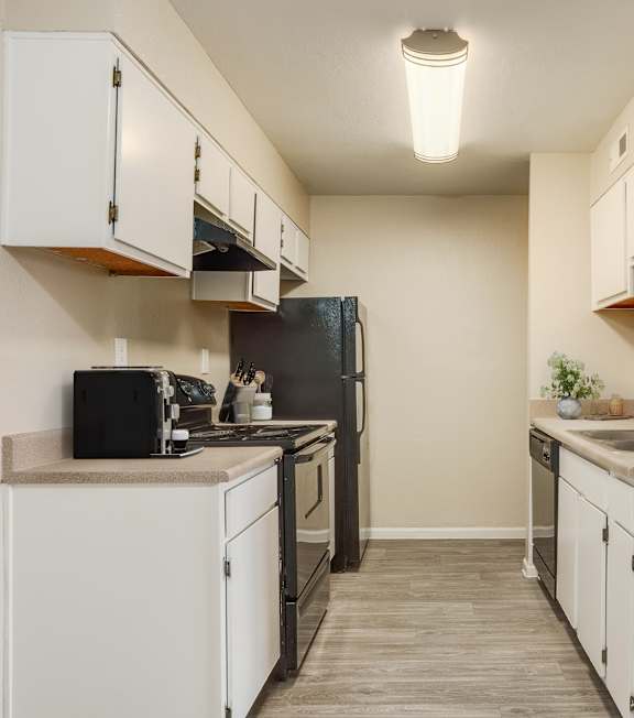 A kitchen with white cabinets and a black refrigerator.