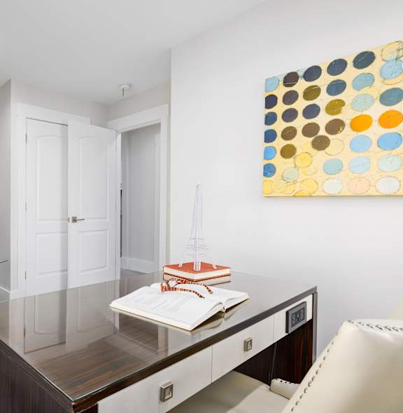 A modern living room with a grey armchair and a painting on the wall.