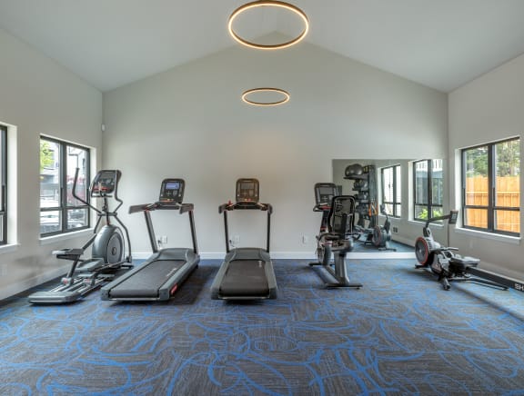 a gym with treadmills and other exercise equipment in a building with windows