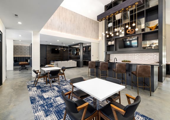 a communal area with tables and chairs and a kitchen and living room