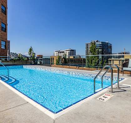 the pool on the rooftop of a building with a city in the background