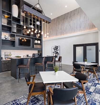 a communal area with tables and chairs and a kitchen and living room