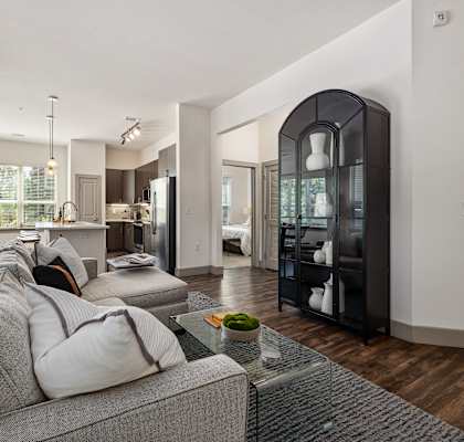 A modern living room with a grey couch and a glass coffee table.